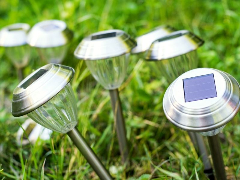 Zewnętrzne oświetlenie solarne w postaci lampek wbitych w trawę.
